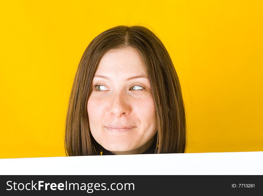 Beautiful woman looking into the left corner. On yellow background