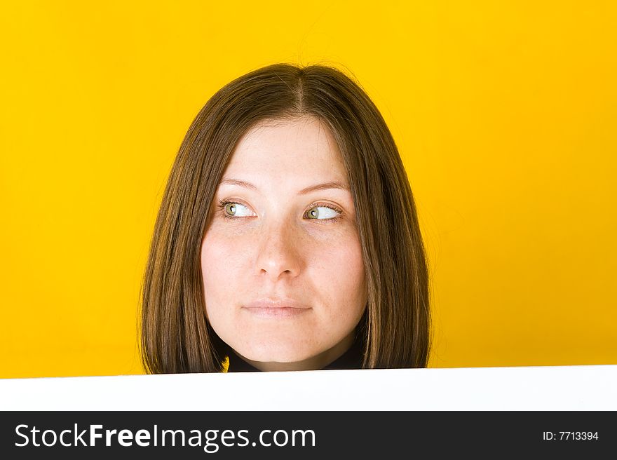 Beautiful woman looking into the left corner. On yellow background