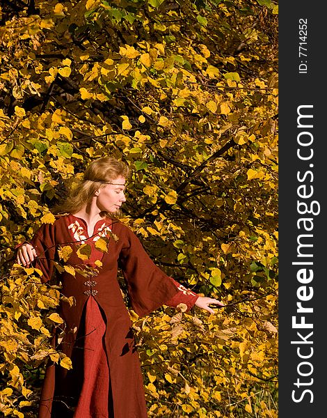 The blonde girl in medieval red dress in the autumn forest. The blonde girl in medieval red dress in the autumn forest