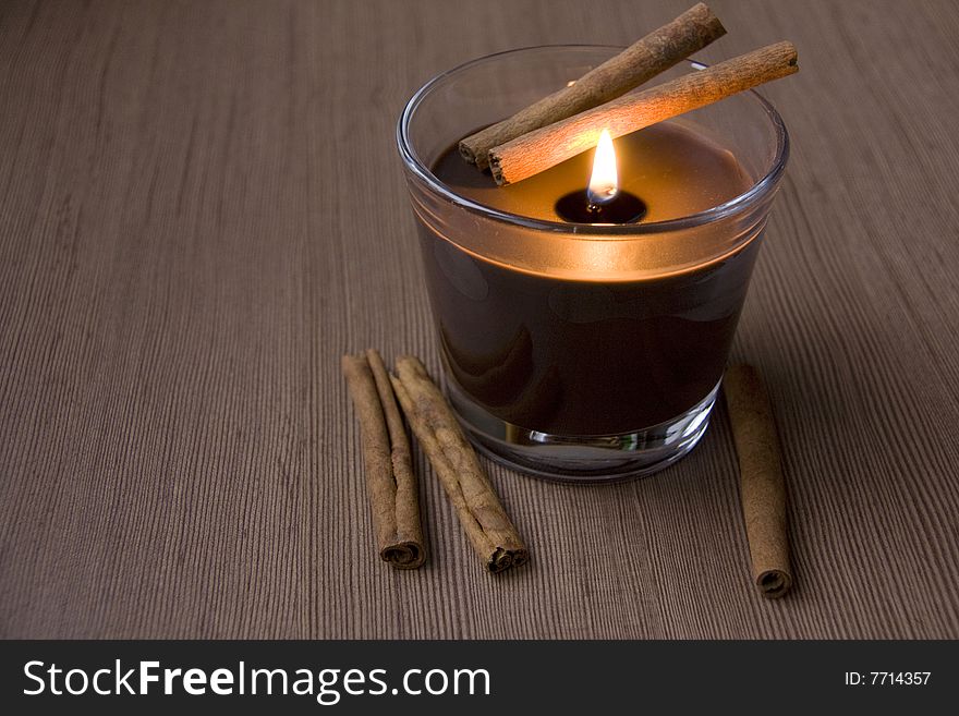 Candle and Cinnamon against the Wooden Surface