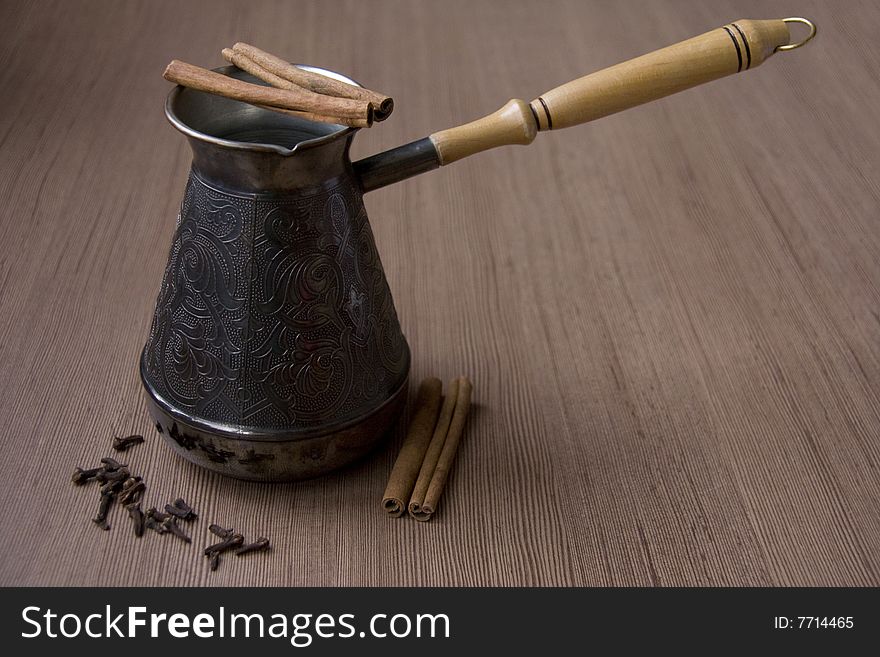 Coffee Pot with Cloves and  Cinnamon against the Wooden Surface