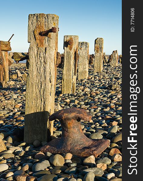 Weathered groynes (sea-defences) and a rusty old bollard. Weathered groynes (sea-defences) and a rusty old bollard