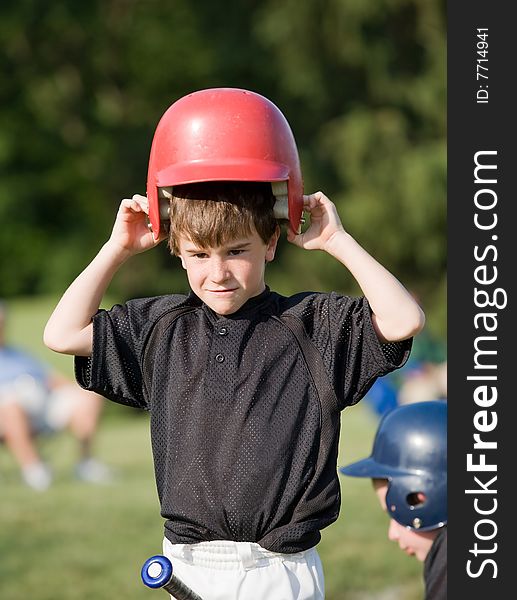 Little Boy Putting on Helmet Getting Ready to Hit. Little Boy Putting on Helmet Getting Ready to Hit