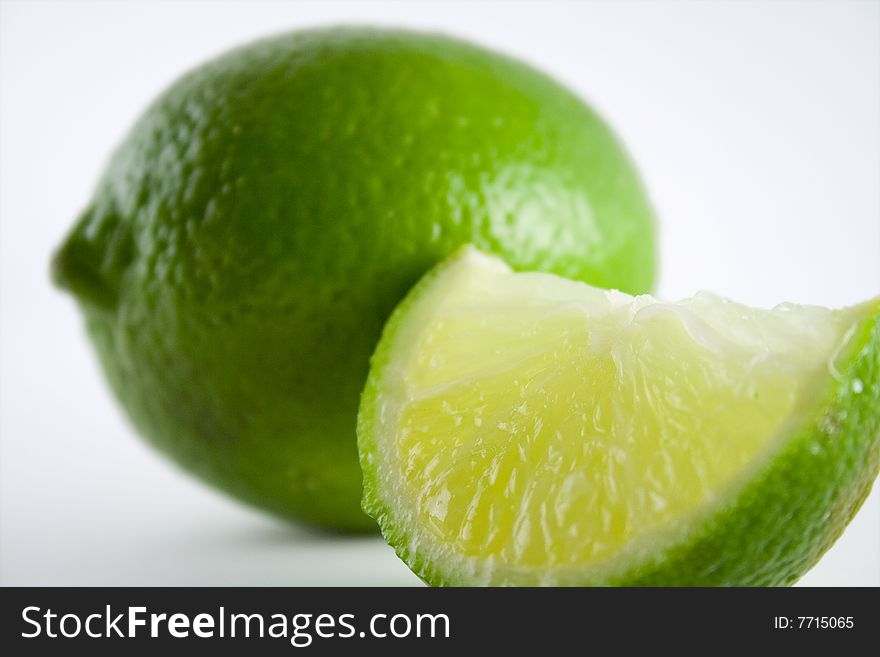 A slice of lime, with a whole lime, on a white background. A slice of lime, with a whole lime, on a white background