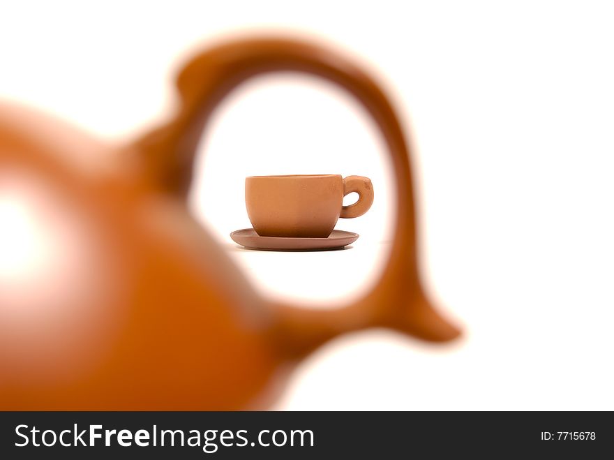 Brown ceramic cup in ear of the teapot on white background