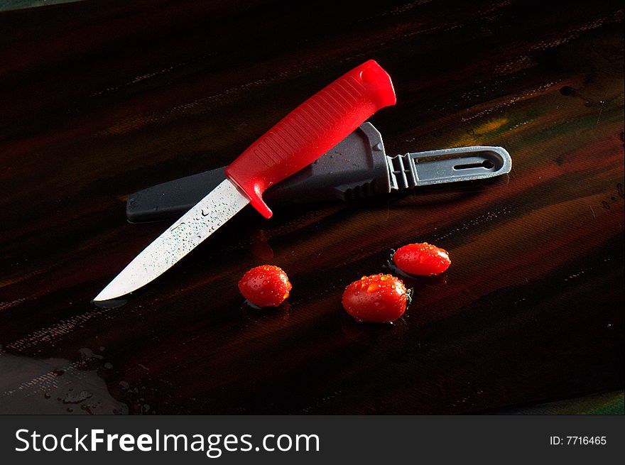 Red knife and small tomatoes. Red knife and small tomatoes