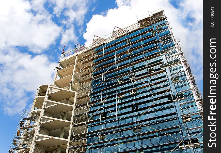 High building of glass and concrete on a blue sky background. 
under construction. High building of glass and concrete on a blue sky background. 
under construction