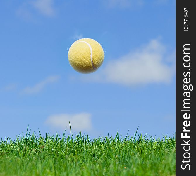Tennis balls fly in the blue sky above green grass field