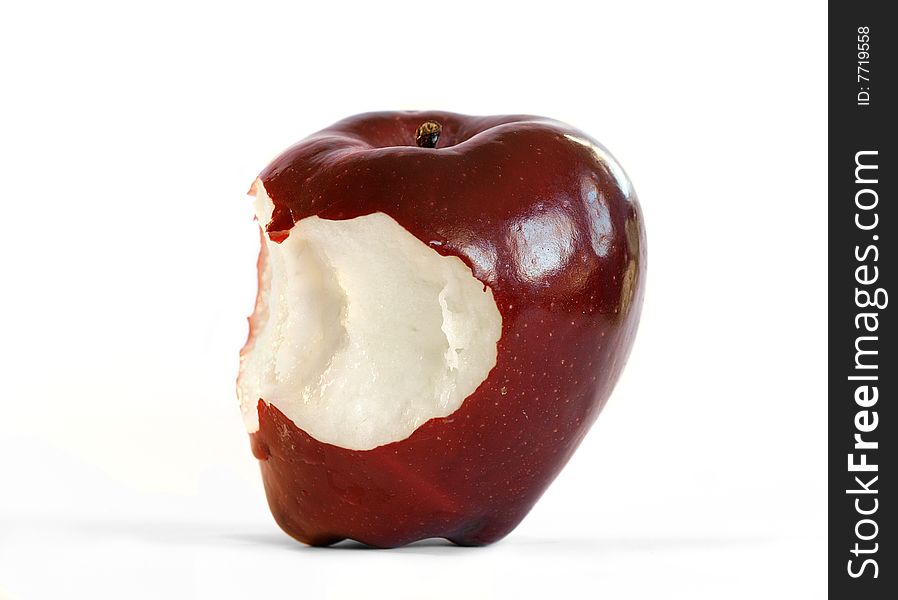 An isolated red delicious apple with two bites taken out of it.