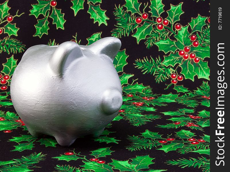 Silver piggy bank on a holy pattern fabric background. Silver piggy bank on a holy pattern fabric background.