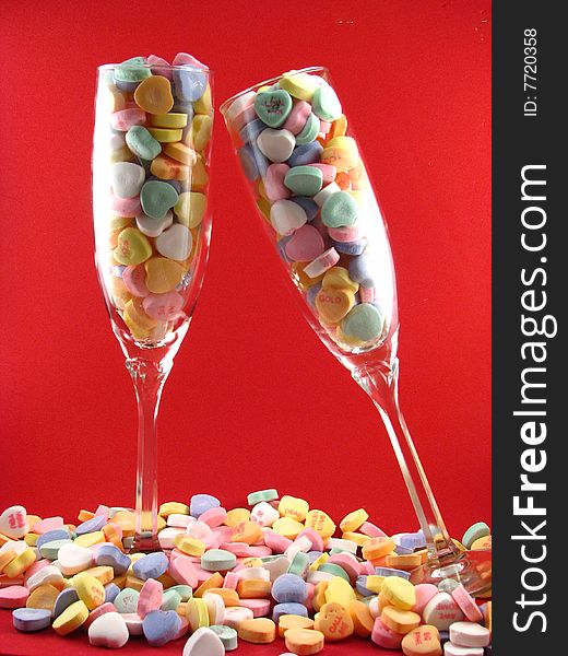 A pair of champagne glasses filled and surrounded by Valentine's Day conversation hearts. A pair of champagne glasses filled and surrounded by Valentine's Day conversation hearts