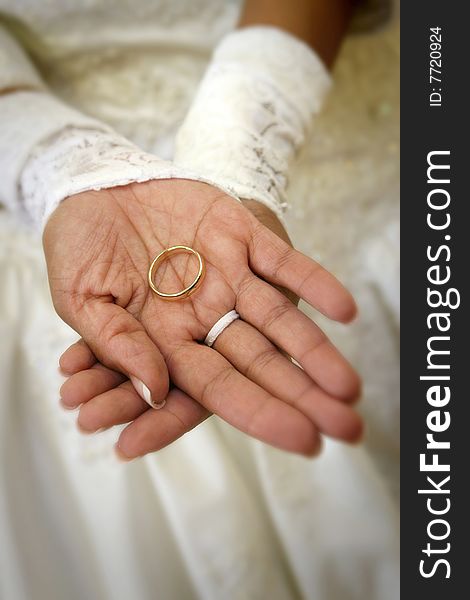 Hispanic bride's hands holding groom's wedding band, shallow dof. Hispanic bride's hands holding groom's wedding band, shallow dof