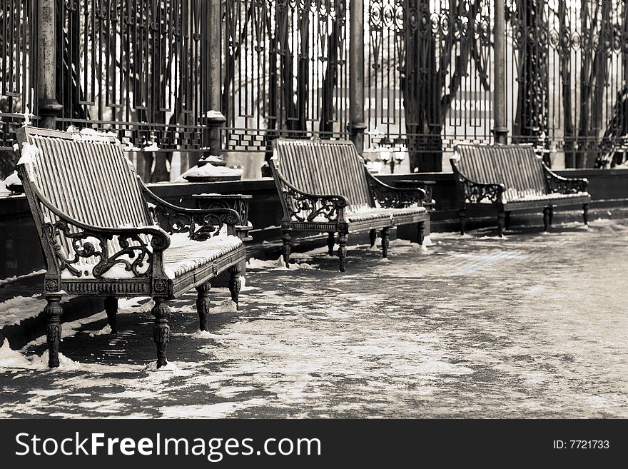 Black and white image of three benches in a park