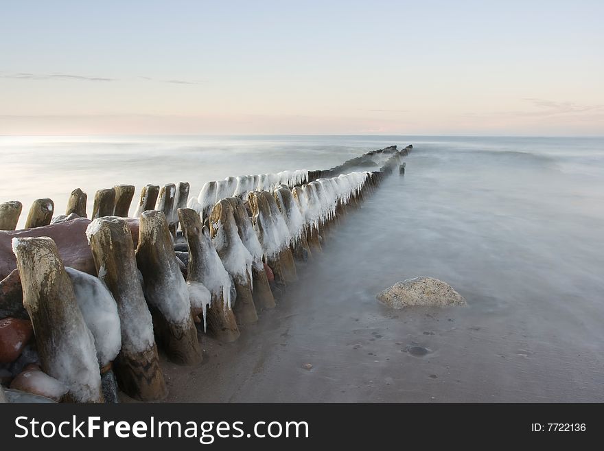 The iced over breakwater on a decline, washed by northern sea