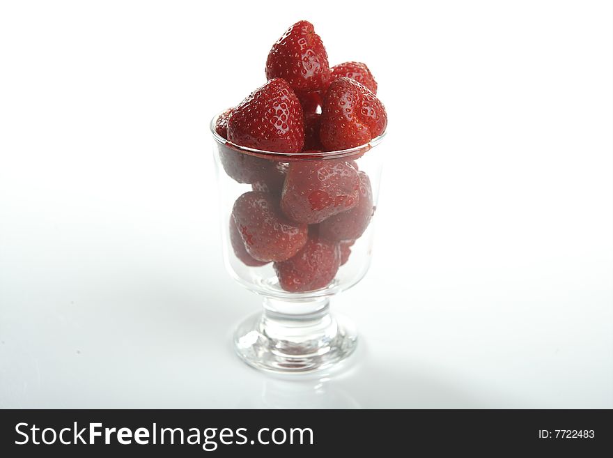 Glass cup full of strawberries in studio white background. Glass cup full of strawberries in studio white background