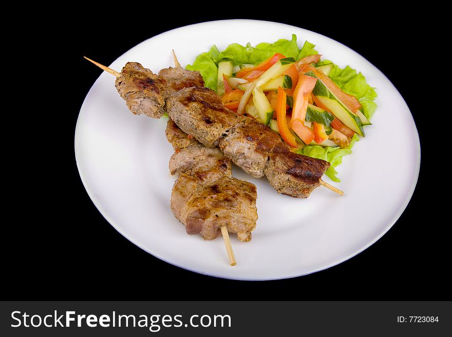 Pork on a grill spit with salad isolated