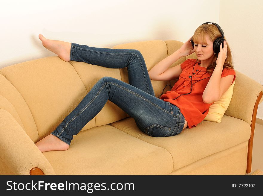 Young woman lying on her sofa, listen to the music.