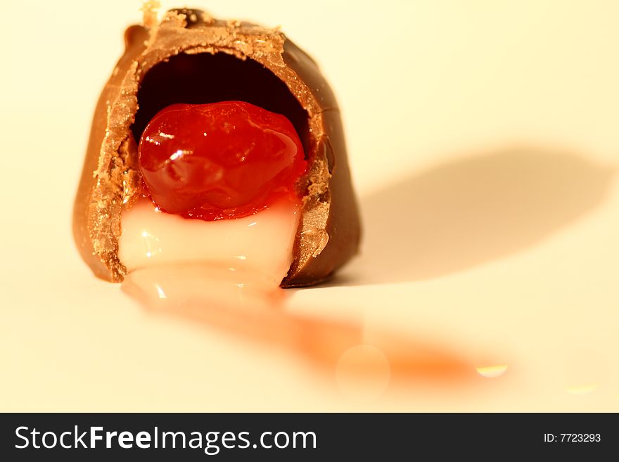 A chocolate covered cherry showing the cream and sugary nougat oozing out.