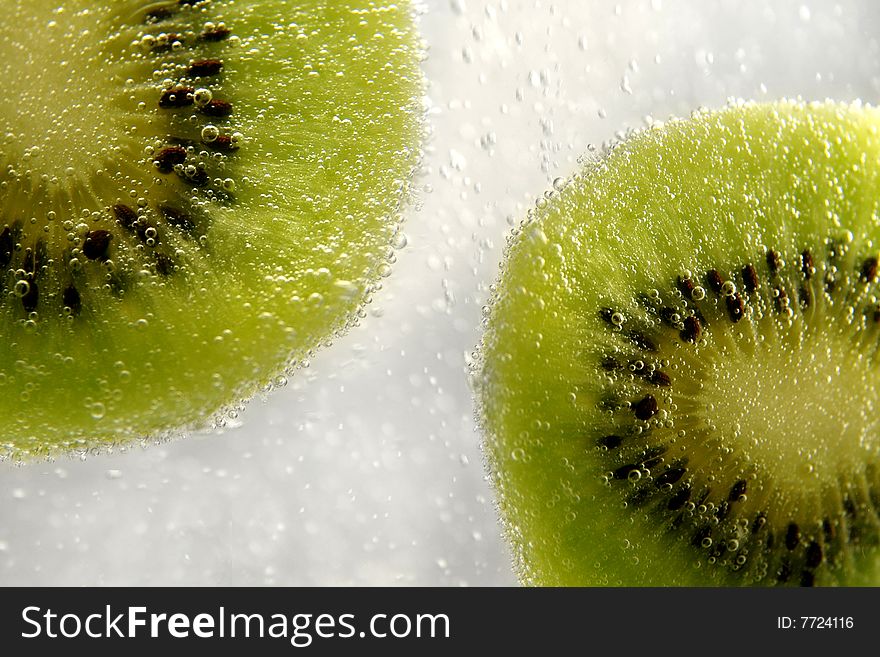 foreground green kiwi pieces in sparkling water