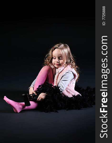 Five years old little cute girl getting dressed for a party. Studio shot on black background. Five years old little cute girl getting dressed for a party. Studio shot on black background.