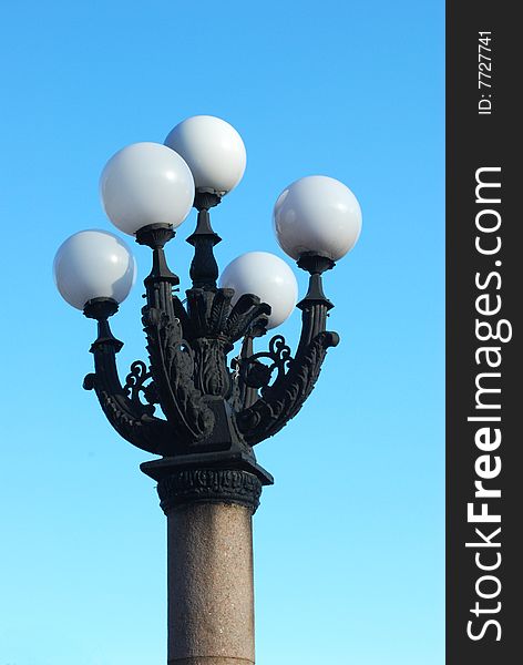 Street lantern with five white lamps against blue sky background
