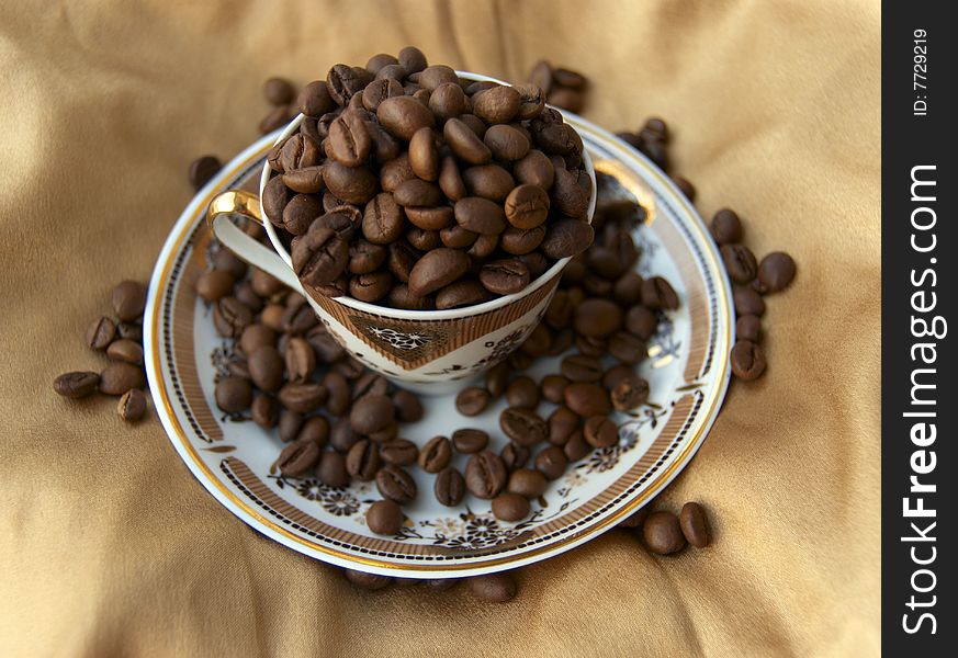 Beautiful cup on the golden silk, full of coffee grains. Beautiful cup on the golden silk, full of coffee grains.