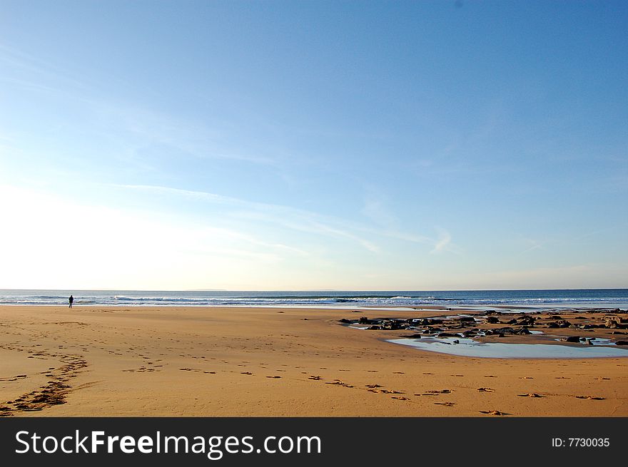 A lone walker on a peaceful beach. A lone walker on a peaceful beach