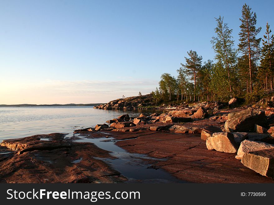 Summer sunrise with forest, water and rocks