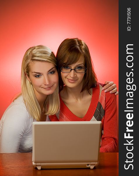 Two beautiful women having fun working with on laptop