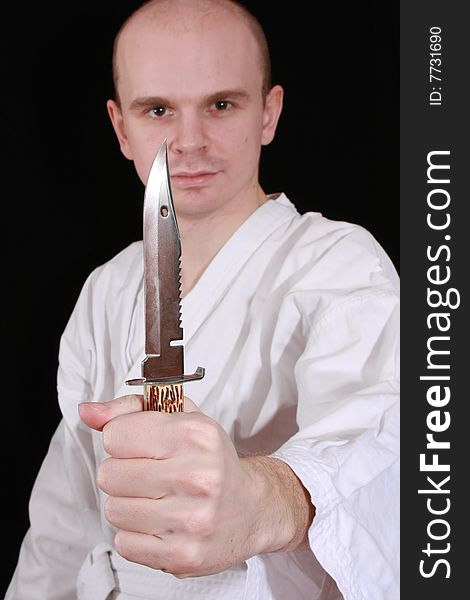 Man in kimono on black background with knife. Man in kimono on black background with knife