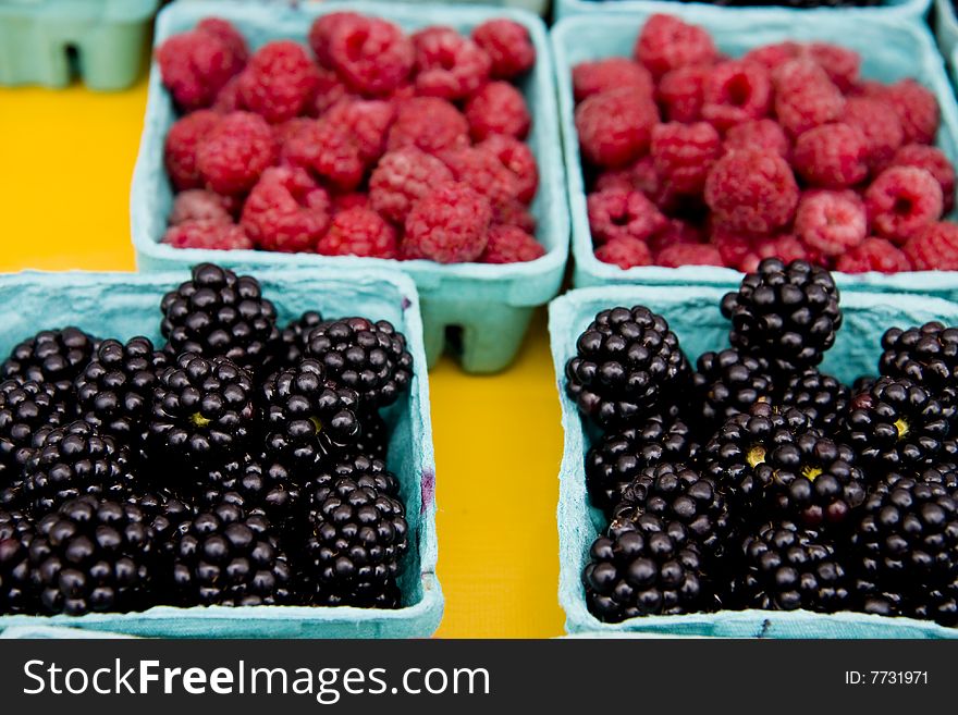 Baskets of fresh blackberries and raspberries in a fruit market