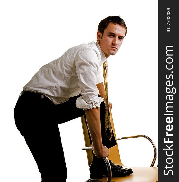 A young businessman with foot in chair looking at camera. A young businessman with foot in chair looking at camera