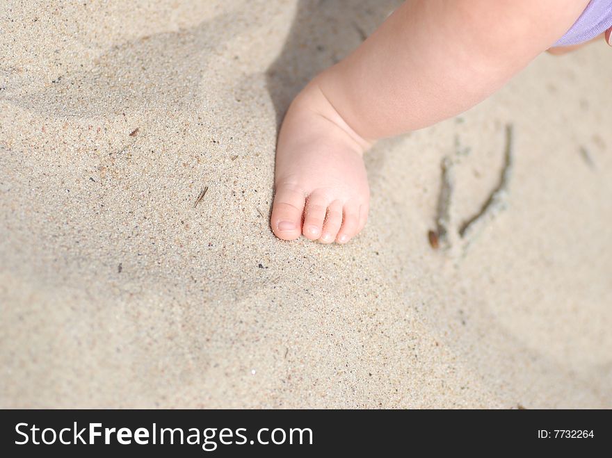 Children's foot on sea sand