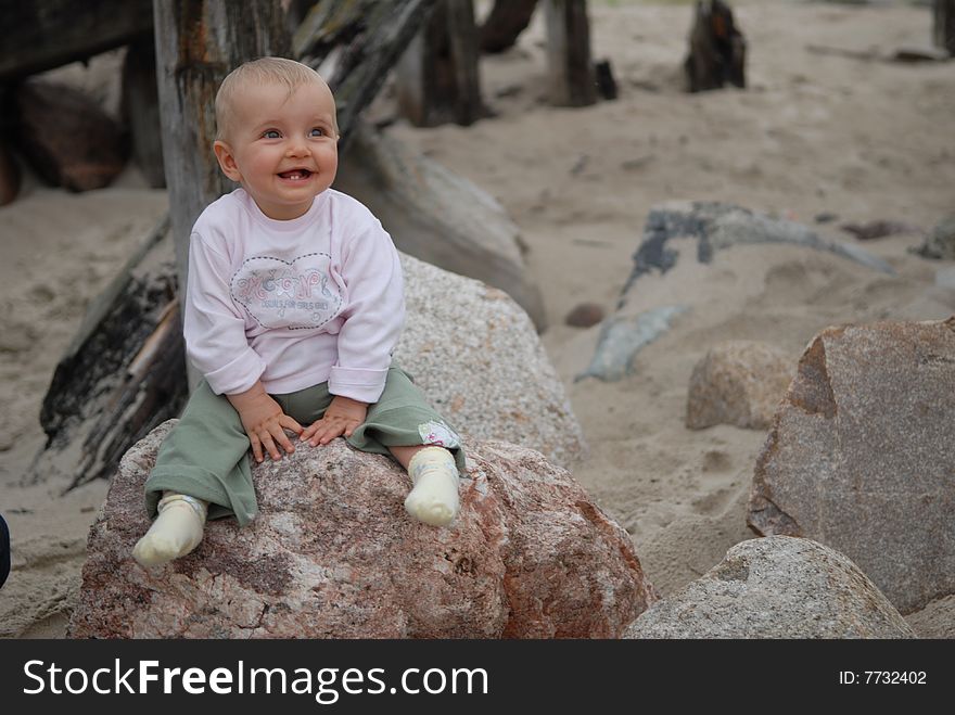 Beautiful child sits on  stone at  sea. Beautiful child sits on  stone at  sea