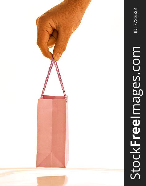 A hand on white background holding a small bag. A hand on white background holding a small bag