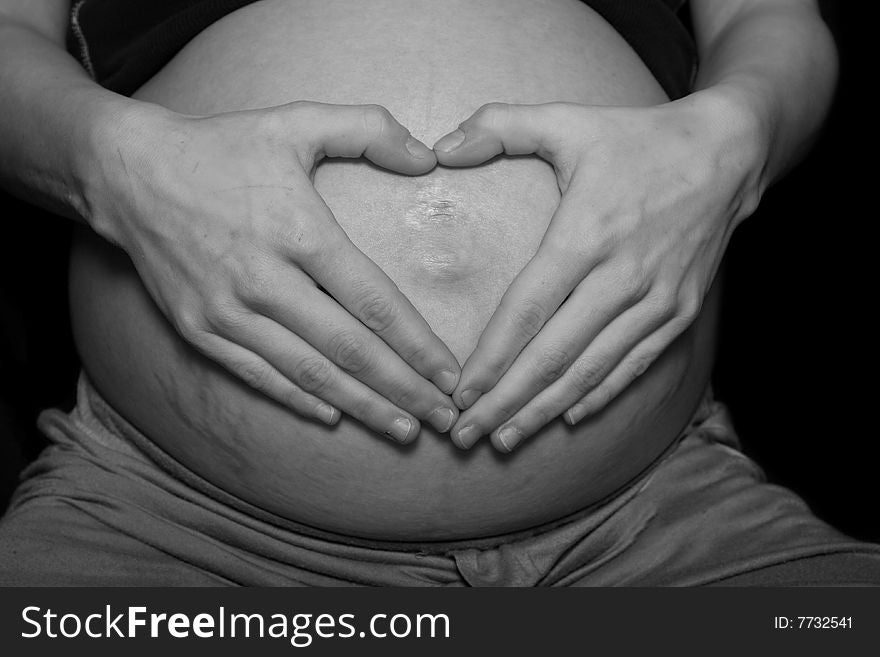 Heart shape made with hands on pregnant belly. Heart shape made with hands on pregnant belly