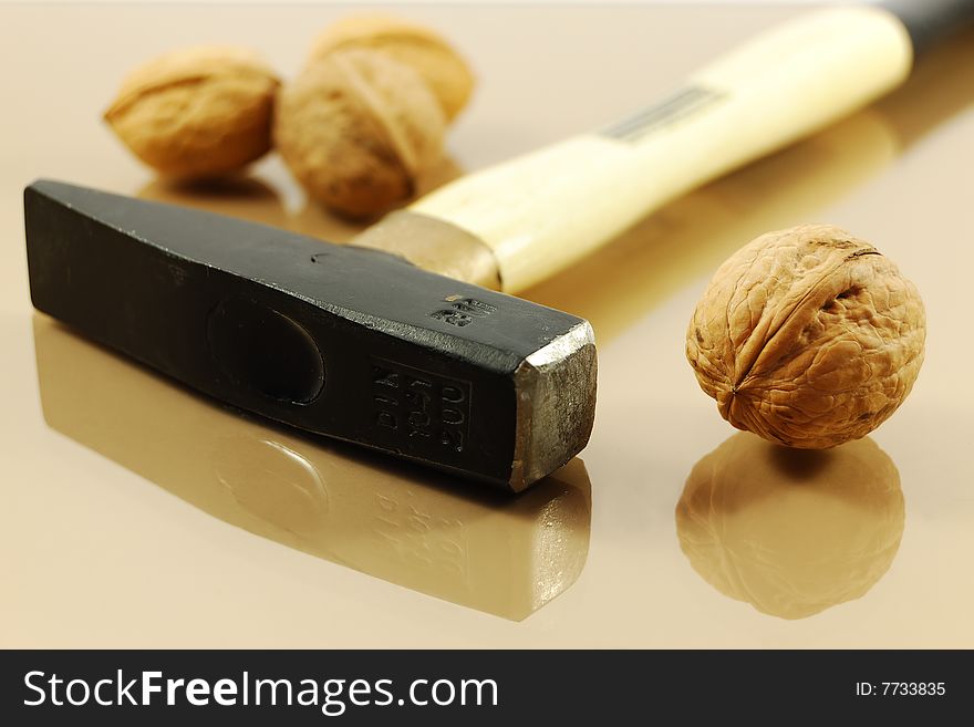 Walnuts and hammer on reflective surface. Tough nut to crack concept.