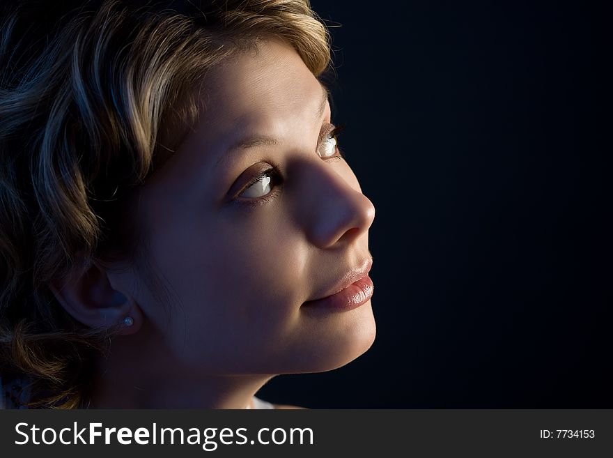 Portrait of pretty blond girl looking up over black with blue illumination