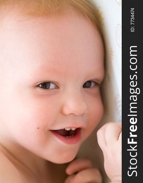 Happy baby lean on the wall. Shallow depth of field. Face close-up  Focus on right eye.