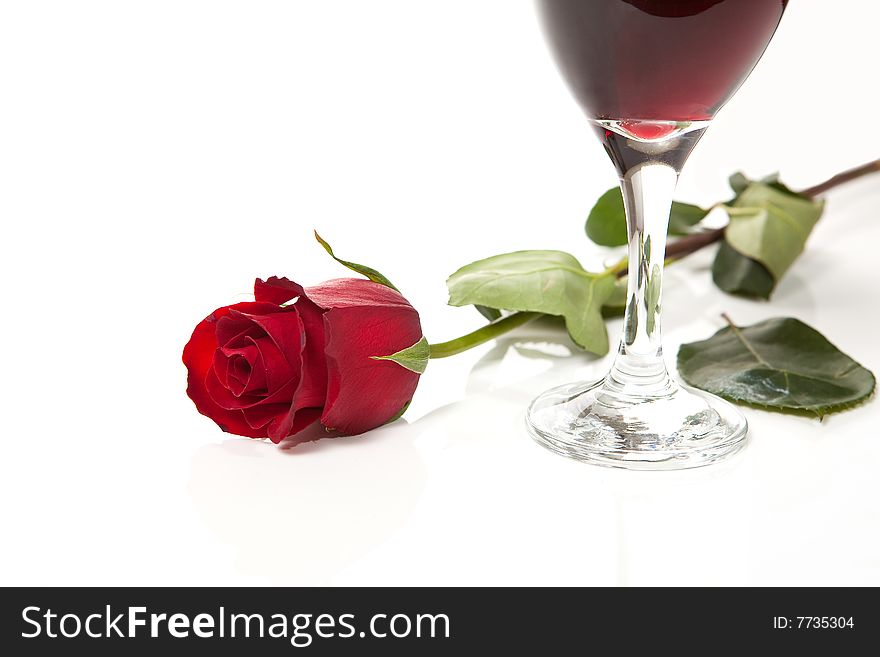 Red rose on white background with glass of red wine