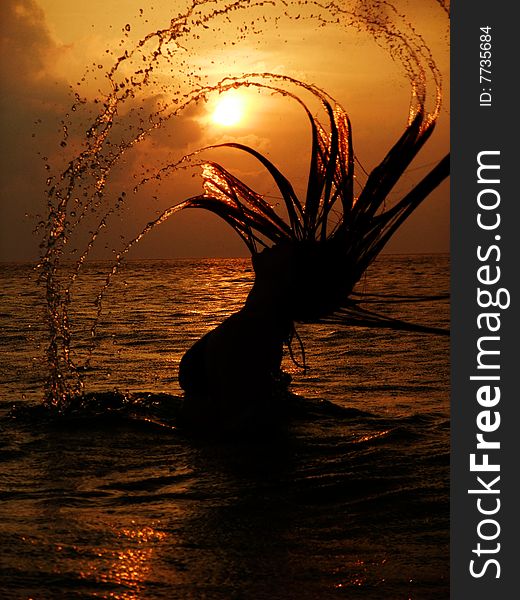 Girl in a water at sunset with long hair and water drops. Girl in a water at sunset with long hair and water drops
