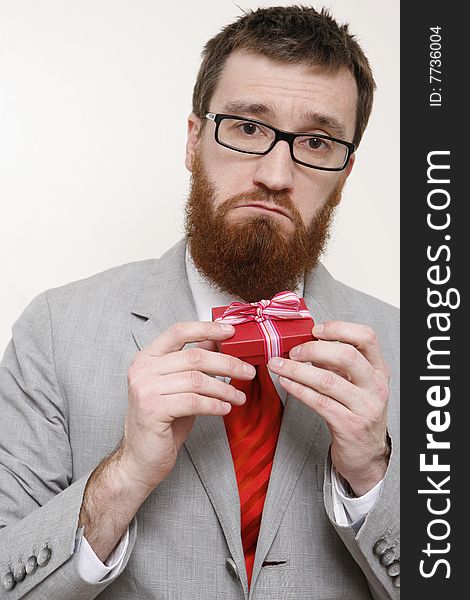Middle aged bearded man holds up a tiny red box as a gift and looks very sad. Middle aged bearded man holds up a tiny red box as a gift and looks very sad.
