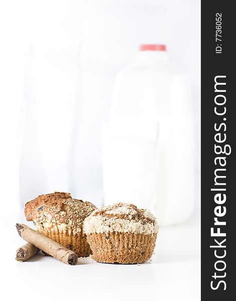 Two muffins on white background with bottle of milk