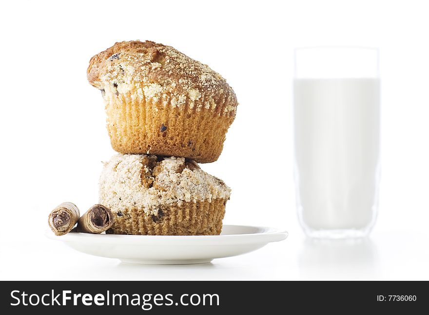 Two freshly baked muffins one over another with glass of milk in the background. Two freshly baked muffins one over another with glass of milk in the background