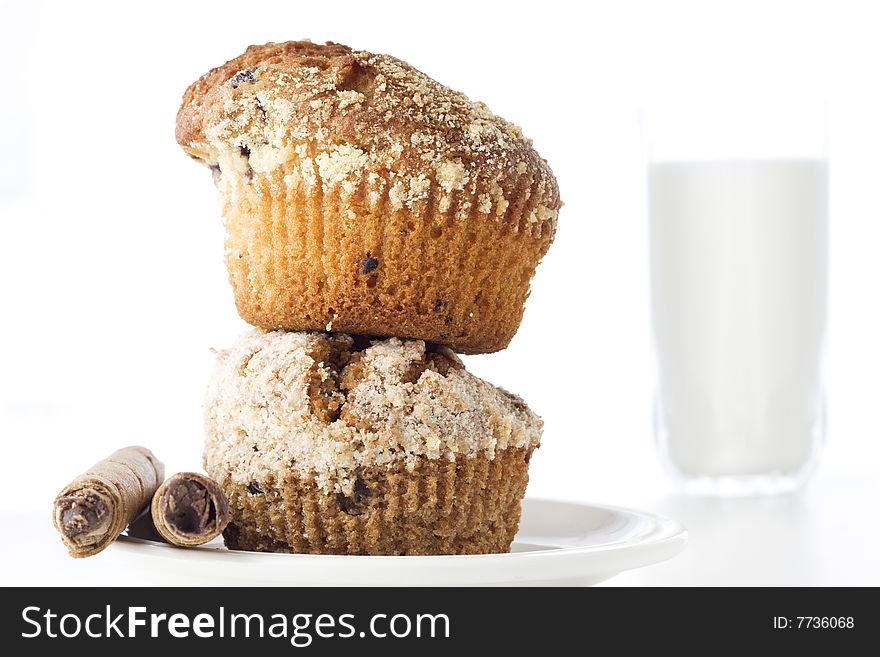 Two freshly baked muffins one over another with glass of milk in the background. Two freshly baked muffins one over another with glass of milk in the background