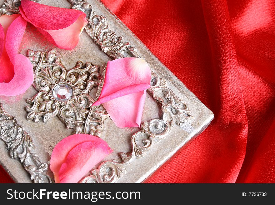 Pink rose petals on a silver ornate box. Pink rose petals on a silver ornate box