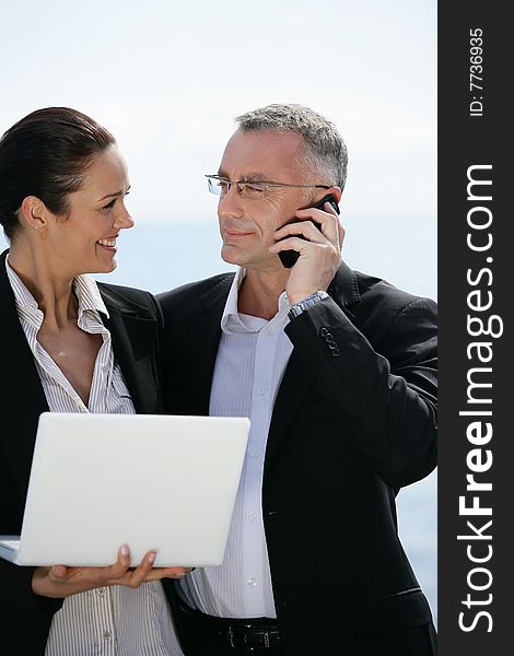 Businessman with mobile phone and businesswoman with laptop computer. Businessman with mobile phone and businesswoman with laptop computer