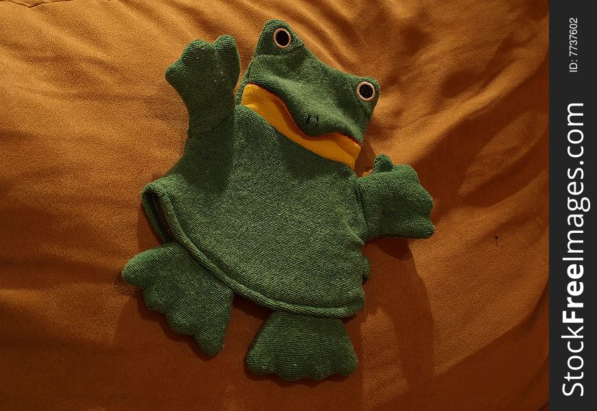 Green plush frog on pillow