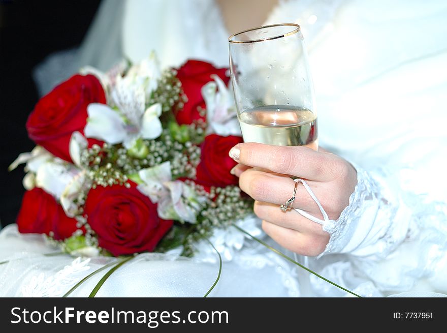 Bride with wedding bouquet and glass of champagne.