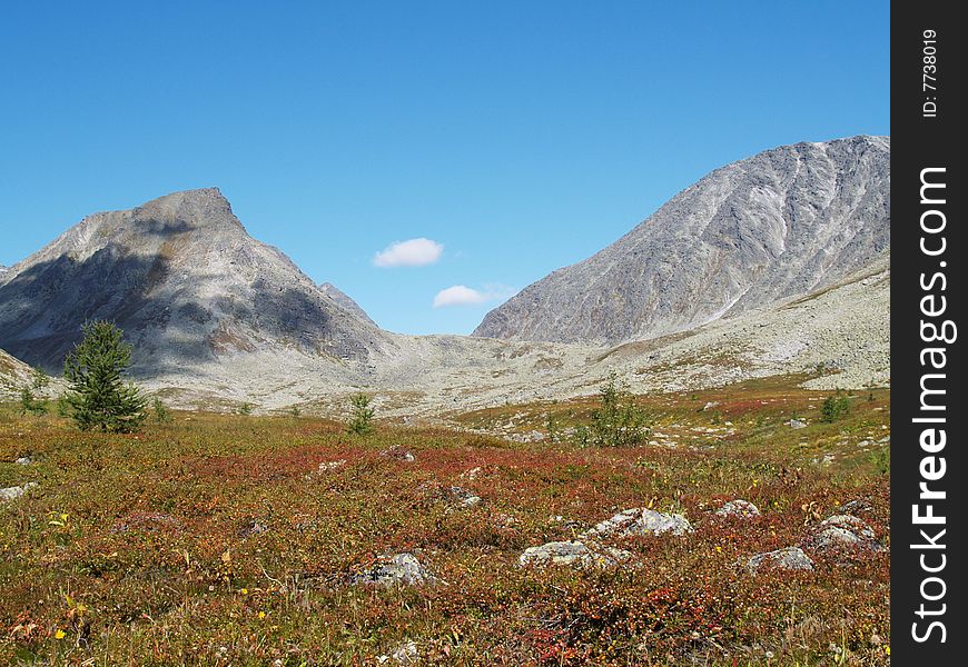 Variegated tundra and mountains against a backdrop of blue sky.